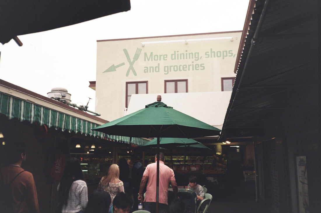 a group of people walking down a street under a green umbrella